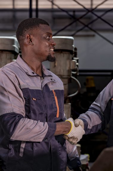 Two confident industrial technicians standing in a machine workshop with arms crossed. Teamwork, skilled labor, engineering, manufacturing, and industrial pride.